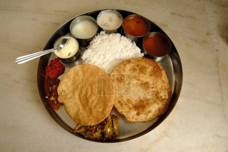 Puri ; plain rice ; two vegetables ; rassam ; curd ; butter milk ; dry chatni ; pickle and papad ; typical south Indian Thali for Lunch at Udupi ; Karnataka ; India