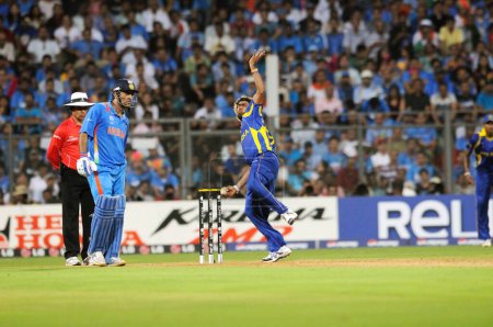 Photo for Sri Lankan bowler Lasith Malinga bowls while Indian batsman M S Dhoni looks on during the 2011 ICC World Cup Final between India and Sri Lanka at Wankhede Stadium on April 2 2011 in Mumbai India - Royalty Free Image
