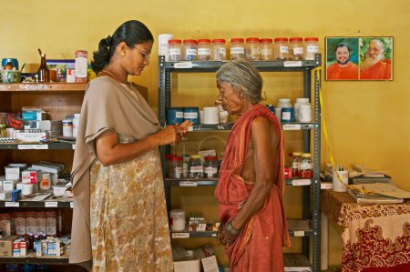 Photo for Health workers of NGO Chinmaya Organization of Rural Development CORD giving medicines to patient at health centre, Siruvani, Karnataka, India - Royalty Free Image