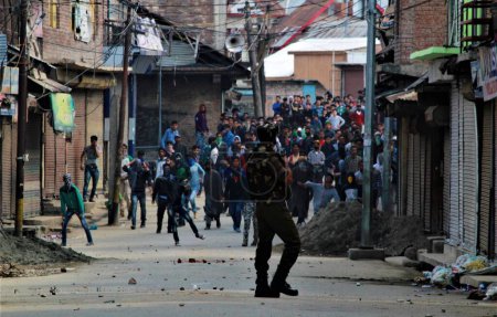 Photo for Kashmiri Muslim protesters throwing stones at policeman, baramulla, Kashmir, India, Asia - Royalty Free Image