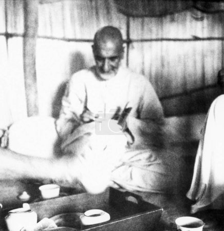 Téléchargez les photos : Khan Abdul Gaffar Khan. assis dans une cabane et écrivant lors de sa visite des zones touchées par les émeutes du Bihar. 1947. Inde - en image libre de droit
