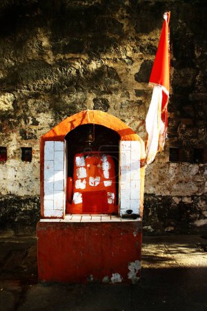 Téléchargez les photos : Petit temple hindou du Seigneur Hanuman dans la cour du temple Shiva, sur les rives de la rivière Narmada, drapeau de couleur orange, le signe de l'hindouisme flotte, Maheshwar, Madhya Pradesh, Inde - en image libre de droit