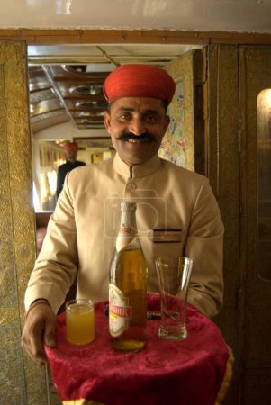 Téléchargez les photos : Rajasthani agent tenant plateau de bière dans le patrimoine sur roues Voyage dans le train touristique de luxe passé ; Rajasthan ; Inde - en image libre de droit
