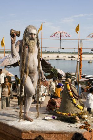 Téléchargez les photos : Hindou saint naga baba Shivdasgiri debout sur un pied et tenant damroo dans la main, Varanasi sur la rivière Ganga, Uttar Pradesh, Inde - en image libre de droit