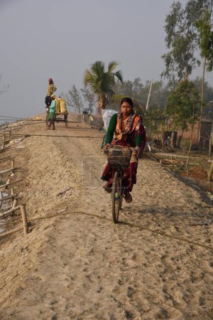 Téléchargez les photos : Femme en vélo, Pakhiralay, Gosaba, Sunderban, South 24 Pargana, West Bengal, Inde - en image libre de droit
