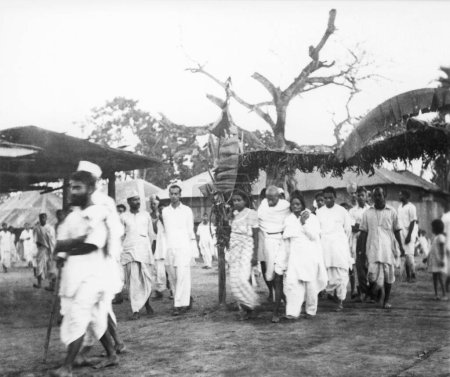 Téléchargez les photos : Mahatma Gandhi, soutenu par Amtus Salam en marche avec d'autres à travers la zone touchée par les émeutes musulmanes hindoues au Noakhali Bengale oriental, novembre 1946, Kanu Gandhi, Inde - en image libre de droit