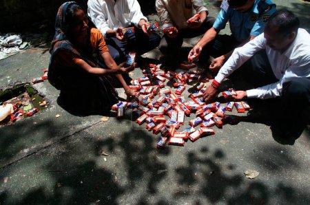Téléchargez les photos : Des gens trient des paquets de biscuits pollués en raison de l'abordage du porte-conteneurs Chitra en mer Bombay Mumbai, Maharashtra, Inde 9-août-2010 - en image libre de droit