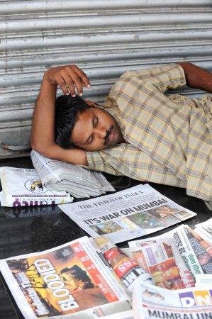 Foto de Hombre durmiendo, artículos periodísticos sobre atentado terrorista por Deccan Mujahideen el 26 de noviembre de 2008 en Bombay Mumbai, Maharashtra, India - Imagen libre de derechos