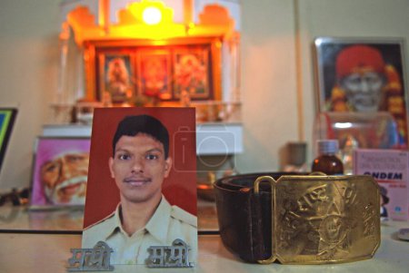 Photo for Police constable Vijay Khandekar photograph and uniform belt kept at his residence of homage after terrorist attack by deccan mujahedeen in Bombay Mumbai. Maharashtra. India 2 December 2008 - Royalty Free Image