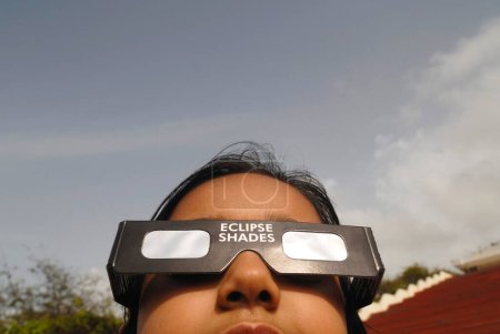 Téléchargez les photos : Une jeune fille regarde l'éclipse solaire partielle en portant un filtre protégé le 1er août 2008 à Bombay Mumbai, Maharashtra, Inde - en image libre de droit
