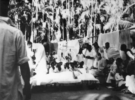 Téléchargez les photos : Mahatma Gandhi, tout en se reposant, parler aux gens dans le Bengale oriental Noakhali après les émeutes entre hindous et musulmans - en image libre de droit