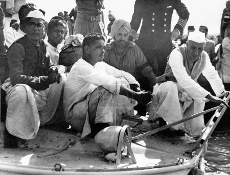 Téléchargez les photos : Jawaharlal Nehru (à droite), Devdas Gandhi (au centre) et Ramdas Gandhi (tenant l'urne) sur le bateau qui les emmène au confluent des rivières Ganges, Yamuna et Saraswati, le 12 février 1948 - en image libre de droit