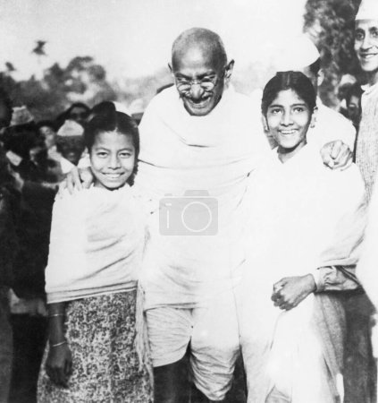 Téléchargez les photos : Mahatma Gandhi, soutenu par deux filles, partageant un rire avec elles, 1945 - en image libre de droit