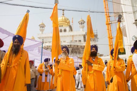 Photo for Orange color dressed Sikh men taking out the procession on the occasion of Guru Ramdas Jayanti out side Akal Takht, Swarn Mandir Golden temple, Amritsar, Punjab, India - Royalty Free Image