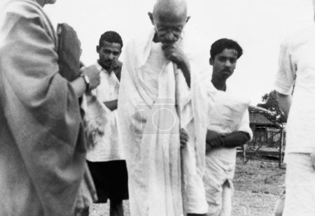 Foto de Mahatma Gandhi caminando con Dhirendra Chatterjee hermano de Abha Gandhi y otros en Sevagram Ashram, 1941 - Imagen libre de derechos