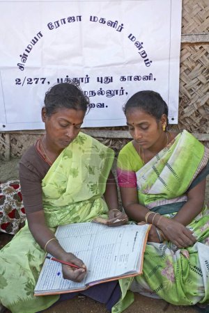 Téléchargez les photos : Mesdames bénévoles de l'ONG Chinmaya Organisation du développement rural CORD tenant à jour le livre de compte de la contribution du financement du microcrédit. Siruvani. Karnataka. Inde - en image libre de droit