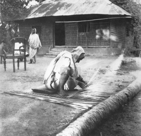 Photo for Mahatma Gandhi. preparing a straw mat in a riot stricken village in Noakhali East Bengal. November 1946. India - Royalty Free Image