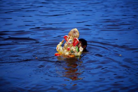 Photo for Idol of Lord Ganesha ganpati Hindu deity being immersed in Powai lake ; Bombay Mumbai ; Maharashtra ; India - Royalty Free Image