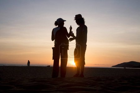 Téléchargez les photos : Deux silhouette humaine parlant près du coucher du soleil ; Palolem plage ; Goa ; Inde - en image libre de droit