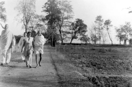 Photo for Khan Abdul Gaffar Khan. Manu Gandhi and Mahatma Gandhi walking through open fields in the riot stricken areas of Bihar. 1947. India - Royalty Free Image
