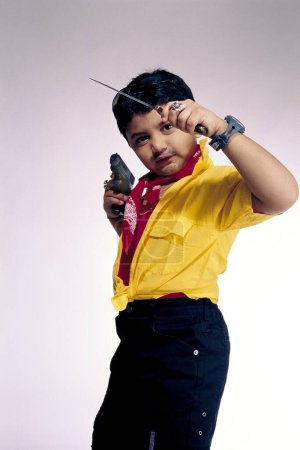 Foto de Niño vestido y actuando como un criminal típico, niño usando ropa elegante y sosteniendo el cuchillo y el arma Rampuri - Imagen libre de derechos