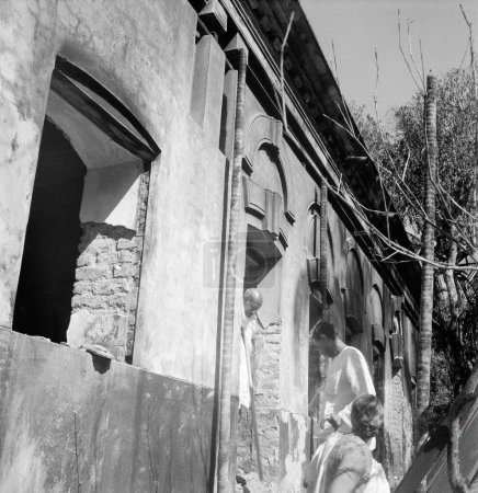 Foto de Mahatma Gandhi dejando un edificio dañado en los disturbios entre hindúes y musulmanes en Noakhali Bengala Oriental. Noviembre de 1946. India - Imagen libre de derechos