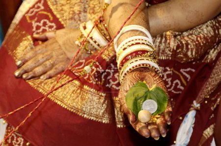 Téléchargez les photos : Mariée indienne d'Asie du Sud tenant Paan bittalnut et pièce d'une roupie dans la cérémonie de mariage urbain, Inde - en image libre de droit