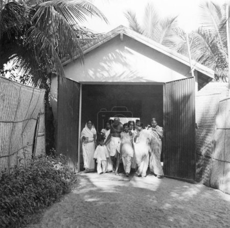 Foto de Mahatma Gandhi, Abha Gandhi, Sushila Nayar y otros caminando a través de una puerta en Madras, 1946, India - Imagen libre de derechos