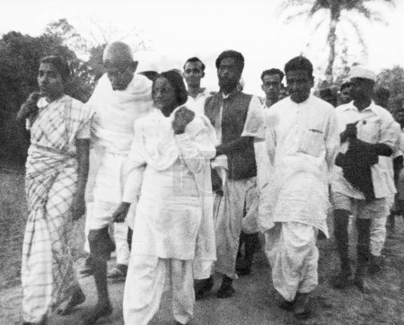 Foto de Mahatma Gandhi, con el apoyo de Amtus Salam y otra mujer, caminando con otros a través de las zonas afectadas por disturbios en Noakhali, Bengala Oriental, noviembre 1946, Arun Guha, India - Imagen libre de derechos