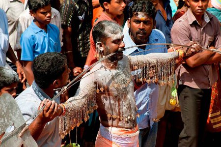 Téléchargez les photos : Homme percant des pointes à travers les joues déchargeant le vœu au festival Thaipusam, Kerala, Inde - en image libre de droit