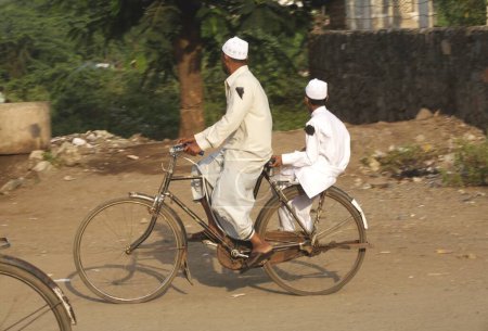 Photo for Black ribbon on shoulder to protest against bomb blast occurred on 29th September 2008, man riding bicycle with his son in textile town of Malegaon, Maharashtra, India - Royalty Free Image