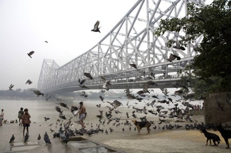 Photo for Activities on Babu ghat ; Howrah bridge over Hooghly river in background ; Calcutta now Kolkata ; West Bengal ; India - Royalty Free Image