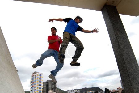 Foto de Dos jóvenes practican diferentes técnicas de salto desde una pared en la estación de tren de Sanpada; Bombay ahora Mumbai; Maharashtra; India - Imagen libre de derechos