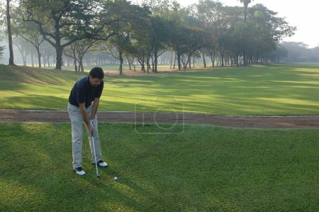 Téléchargez les photos : Homme jouant au golf en position pour frapper la balle, balle de golf et club, Golf Club, Chembur, Mumbai Bombay, Maharashtra, Inde - en image libre de droit