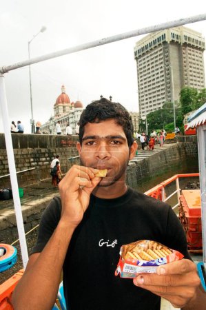 Photo for Man eating oil soaked biscuit packets due to container ship chitra colliding in sea Bombay Mumbai, Maharashtra, India - Royalty Free Image