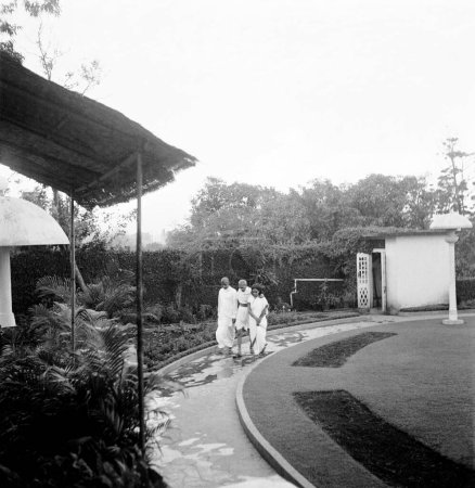 Foto de Mahatma Gandhi. caminando con Sushila Nayar y R.D. Birla en Birla House. Mumbai. 1945. India - Imagen libre de derechos