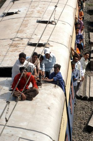 Téléchargez les photos : Garçons qui font la navette assis sur le toit des trains locaux - en image libre de droit