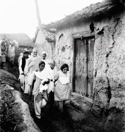 Photo for Mahatma Gandhi, supported by Mridulabehn Sarabai and Manu Gandhi, walking with Khan Abdul Gaffar Khan and others through a village of the riot stricken areas of Bihar, 1947, India - Royalty Free Image