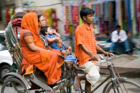 Téléchargez les photos : Cycle Rickshaw Rider avec passagers, trafic à Dacca, Bangladesh - en image libre de droit