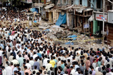 Photo for Policemen inspecting bomb blast site crowd gathered to see at Zaveri Bazaar in busy Kalbadevi area, Bombay Mumbai, Maharashtra, India August 26th 2003 - Royalty Free Image