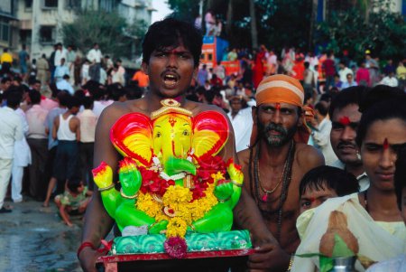 Téléchargez les photos : Homme portant statue de Ganesh ganpati Festival Elephant head Lord immersion, dadar chowpati, bomay mumbai, maharashtra, Inde - en image libre de droit