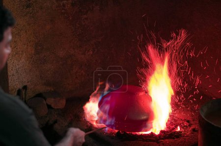 Téléchargez les photos : Homme chauffant un récipient en cuivre dans un four à combustion Pune Maharashtra Inde Asie - en image libre de droit