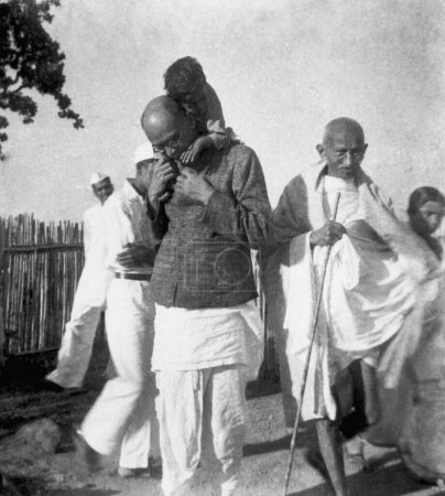 Foto de Mahadev Desai, llevando a un niño sobre sus hombros, Mahatma Gandhi y otros en el Ashram Sevagram, 1940 - Imagen libre de derechos