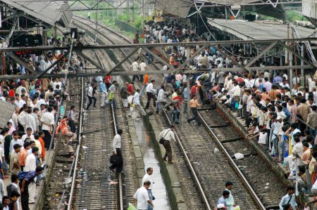 Téléchargez les photos : Les navetteurs traversent dangereusement les voies ferrées pour attraper un train local risquant leur vie à la gare de Ghatkopar à Bombay Mumbai, Maharashtra, Inde - en image libre de droit