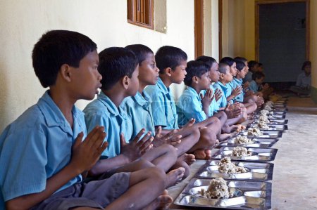 Foto de Niños en escuela rural rezando antes de comer socio, actividad económica de la ONG Chinmaya Organización de Desarrollo Rural CORD, Deuladiha, Orissa, India - Imagen libre de derechos