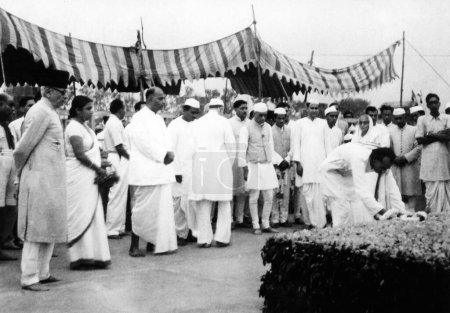 Foto de Personas rindiendo homenaje en Rajghat, Delhi, donde tuvo lugar el funeral de Mahatma Gandhis, 1948, Abdul Kalam Maulana Azad, Sucheta Kripalani, Shem Prasad Mukherjee, Jawaharlal Nehru, Acharya Kripalani, colocando una guirnalda de flores, India - Imagen libre de derechos