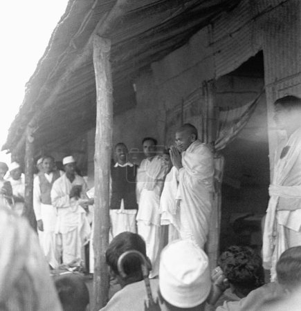 Foto de Mahatma Gandhi saluda a la gente frente a la cabaña Kasturba Gandhis en Sevagram Ashram, 1945, India - Imagen libre de derechos