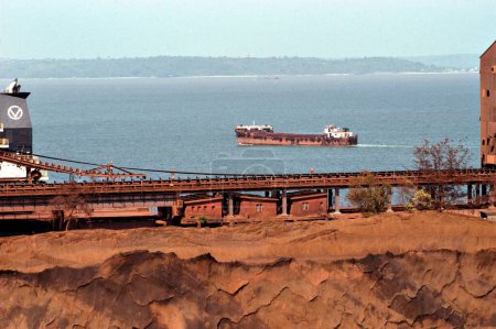 Transporte marítimo; mineral de hierro a la espera de ser cargado en buques graneleros en capacidad llena Mormugao Puerto Confianza muelle en Vasco en el suroeste de Goa; India