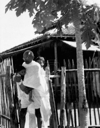 Téléchargez les photos : Mahatma Gandhi portant un enfant Shardabehns à l'ashram de Sevagram, 1940 - en image libre de droit