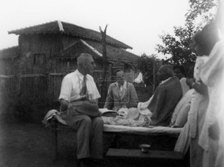 Foto de Mahatma Gandhi reuniéndose con visitantes de Inglaterra en el Ashram Sevagram, 1940, Pyarelal Nayar, Sushila Nayar ambos medio cubiertos - Imagen libre de derechos